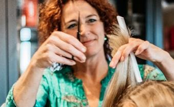 Carola, kapper bij De Kapperszaak van..., knipt het haar van een klant.